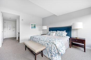 A bedroom with a blue and white bed and white carpet